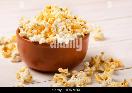 Cheesy popcorn in una ciotola marrone sul tavolo di legno Foto Stock