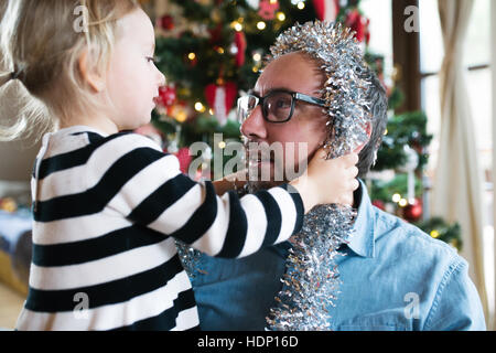 Padre con daugter decorare albero di Natale. Similrame argento su Foto Stock
