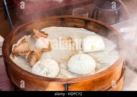 Giappone, Kobe Nankinmachi, Chinatown. Dim sum, pancetta di maiale Bun e riso, dumplins zong, essendo a vapore in contenitore di legno. Close-up. Foto Stock