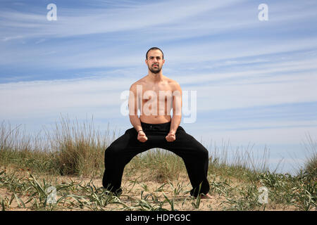 Giovane maschio fighter esercitando su di una collina di sabbia Foto Stock