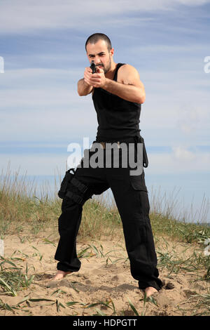 Giovane maschio del bodyguard in possesso di una pistola Foto Stock