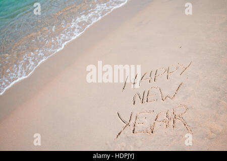 Felice Anno Nuovo scritto nella sabbia bianca Foto Stock