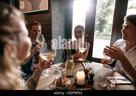 Piscina colpo di giovani amici bevendo vino presso il cafe. Un gruppo di uomini e donne gustando un bicchiere di vino presso il ristorante.