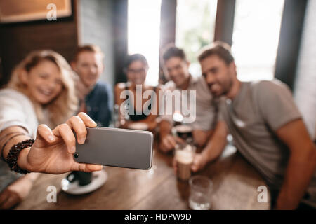 Un gruppo di giovani di prendere una selfie presso il cafe. Giovani amici presso il ristorante tenendo self portrait. Foto Stock