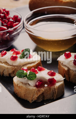 Pane con formaggio cremoso i semi di melograno e miele Foto Stock