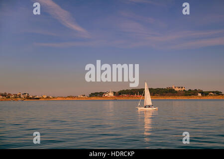 Barca a vela al tramonto sulla baia di Santander. Sullo sfondo la città, vista dal villaggio di Pedreña, Cantabria, Spagna, Europa Foto Stock