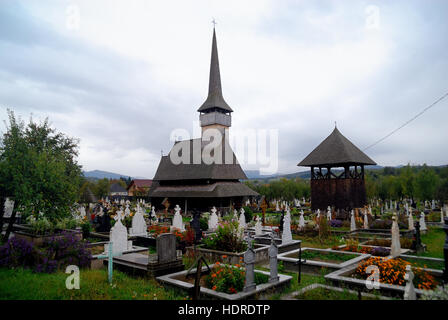 Maramures, isolata regione dei Carpazi della Romania. Il cimitero di Rozavlea, con la sua chiesa di legno, costruito nel 1717 dedicato ai santi arcangeli Michele e Gabriele. Foto Stock