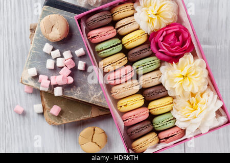 Amaretti colorati su un tavolo di legno. Dolce macarons in confezione regalo. Vista superiore Foto Stock