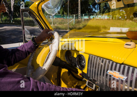 Conducente al volante di una Chevrolet gialla, old anni cinquanta vettura americana, nota lettura della velocità digitale sotto il cruscotto, La Havana, Cuba. Foto Stock
