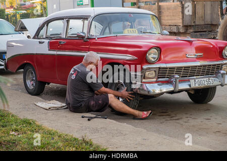 Taxi driver riparazione ruota sulla sua vettura, 1950s vecchio American Chevrolet, Vinales, Cuba Foto Stock
