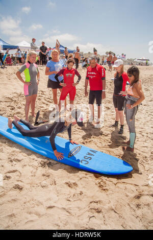 Grazie per il suo servizio militare, un veterano (centro) riceve gratuitamente una lezione di surf da un istruttore femmina dall'Oceano Pacifico in Huntington Beach, CA. Foto Stock