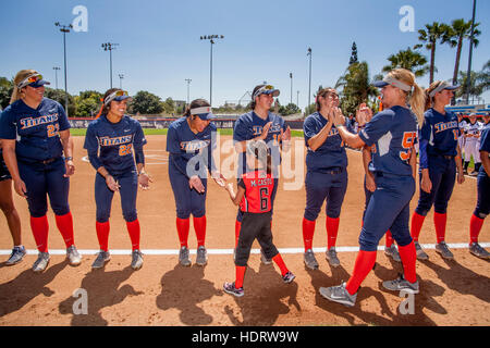 Multirazziale college femminile giocatori di softball agitare le mani con una ragazza giovane ammiratore che si preparano per un gioco sul campo in Fullerton, CA. Foto Stock