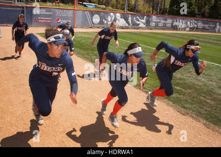 Multirazziale college femminile giocatori di softball sprint che si preparano per un gioco sul campo in Fullerton, CA. Foto Stock