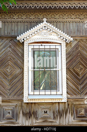 Finestra con motivi scolpiti su una vecchia casa in legno Foto Stock