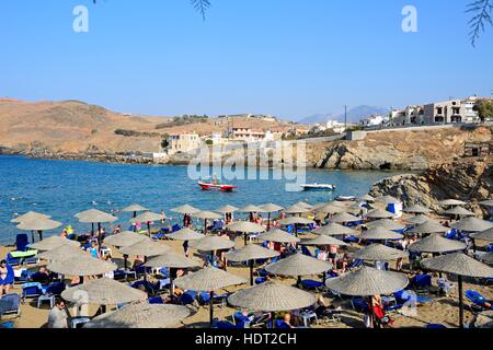 I turisti rilassante sulla spiaggia sabbiosa con vista verso il mare Egeo e la costa rocciosa, Panormos, Creta, Grecia, l'Europa. Foto Stock