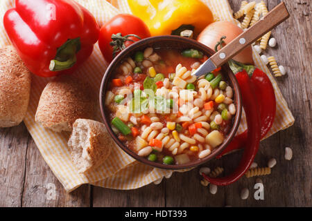 Italian minestrone di verdure zuppa in una ciotola e gli ingredienti sul tavolo. vista orizzontale al di sopra di close-up Foto Stock