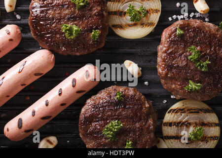 Hamburger e salsicce con verdure grigliate macro. vista orizzontale dal di sopra Foto Stock