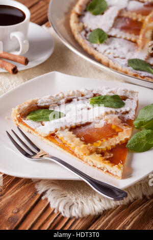 Pezzo di torta italiana con marmellata di albicocche e caffè sul tavolo. In verticale Foto Stock