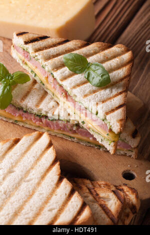 Panino caldo con prosciutto e formaggio e basilico vicino sul tavolo. In verticale Foto Stock