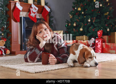 Donna con beagle in camera con decorazioni di Natale Foto Stock
