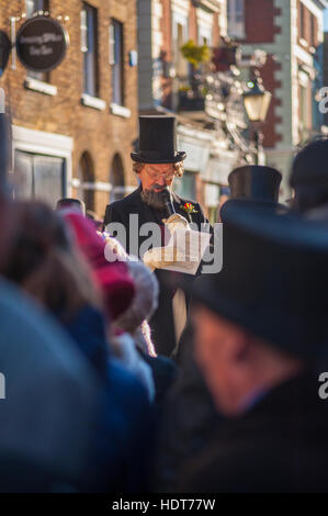 Attore vestito come Charles Dickens lettura per la folla della 2016 Dickensian Festival di Natale in Rochester Kent Foto Stock