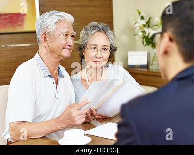 Senior coppia asiatici sembrano essere scettici dopo la lettura di una proposta Foto Stock