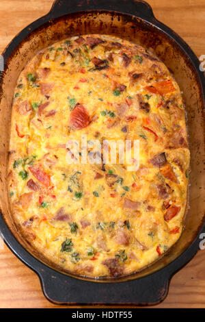 Stile Italiano frittata, uova ricetta pomodori cipolle, i piselli e i peperoni in capsula di vetro Foto Stock