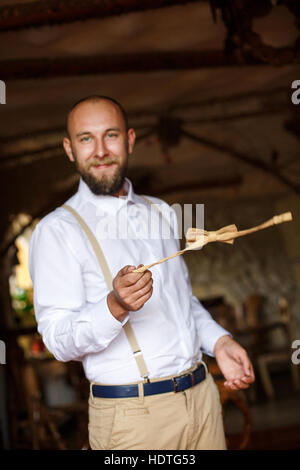 Uomo Barbuto torcendo il filtro bow tie in mano Foto Stock