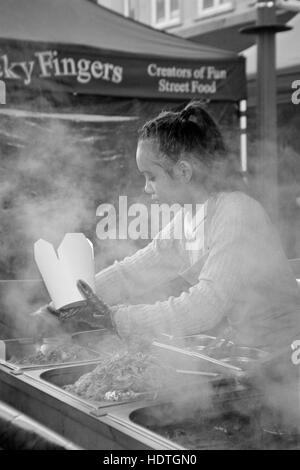 Giovane bella donna tailandese che serve cibo di strada in un mercato in stallo palmerston road southsea England Regno Unito Foto Stock