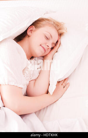 Donna che dorme nel letto bianco Foto Stock