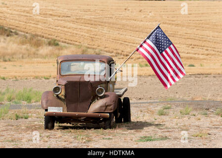 Vecchia Ford carrello dello scanner a superficie piana con una bandiera americana in una fattoria in Eastern Washington. Foto Stock