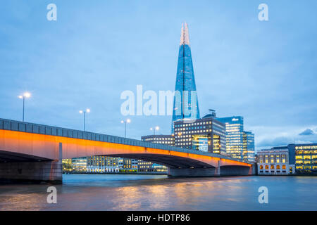 Lo skyline di Londra al tramonto con il London Bridge e il Coccio in vista sul fiume Tamigi Foto Stock