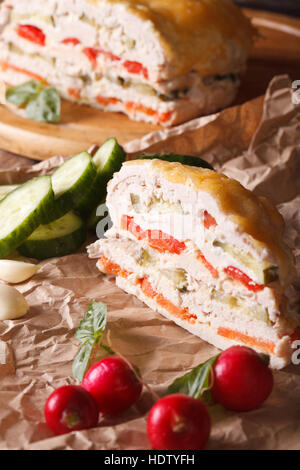 Un pezzo di torta di pollo con verdure e formaggio su carta verticale. Foto Stock