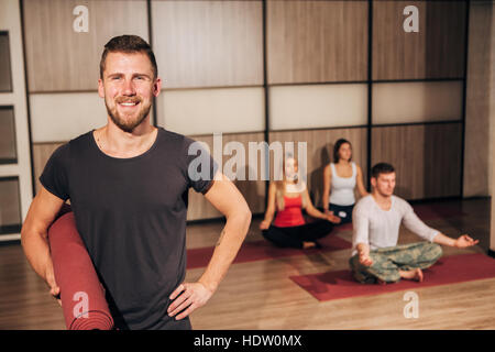Ritratto di un uomo con materassino yoga e sorridente con la sua mano dietro la testa Foto Stock