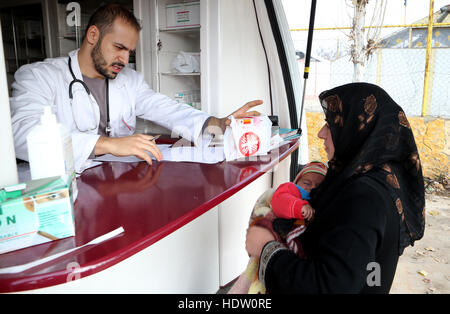 Un farmacista che volontari per la Caritas mobile clinica medica distribuisce medicinali ai rifugiati siriano in un campo nei pressi di Taalabaya nella valle della Bekaa. Foto Stock