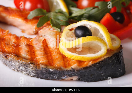 Salmone alla griglia bistecca con il limone su di una piastra orizzontale di macro Foto Stock