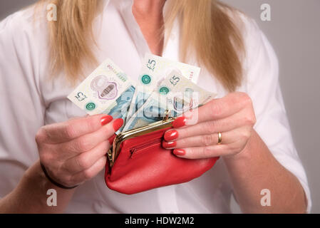 Donna di mani tenendo un portamonete rosso contenente il nuovo regno Unito cinque pound note Foto Stock