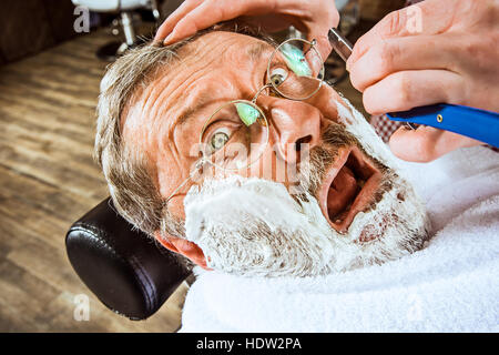 Il senior uomo visitando un parrucchiere in un barbiere. Foto Stock