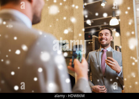 Uomo in tuta prendendo selfie specchio al negozio di abbigliamento Foto Stock