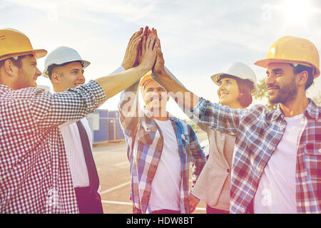 Close up dei costruttori in hardhats rendendo alta cinque Foto Stock