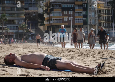 Spiaggia affollata scena con principalmente donne e uomini anziani o rilassante esercizio, incline uomo in primo piano Foto Stock