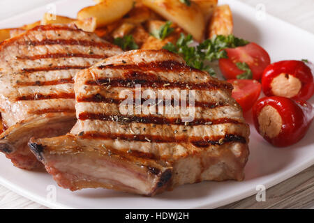 Carne di maiale alla griglia bistecca con patate e verdure su una piastra macro. orizzontale Foto Stock