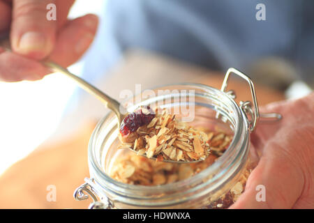 Un uomo di muesli rimuove un vasetto con un cucchiaio Foto Stock