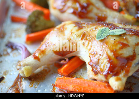 Pollo arrosto con foglie di salvia fresca, carote, broccoli e cipolle su una teglia Foto Stock