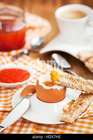 Uova sode con caviale rosso, pane tostato e caffè per colazione Foto Stock