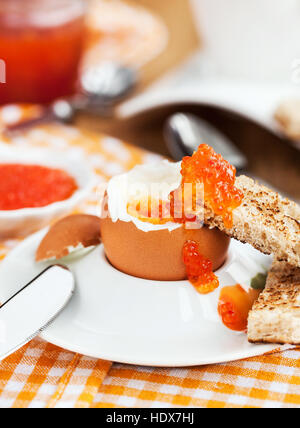 Uova sode con caviale rosso, pane tostato e caffè per colazione Foto Stock