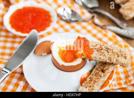 Uova sode con caviale rosso, pane tostato e caffè per colazione Foto Stock