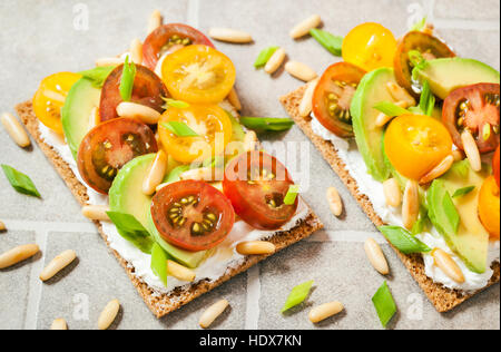 Una sana della Segala croccante pane tostato con crema di formaggio fresco di avocado, pomodorini e pinoli Foto Stock