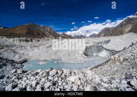 Vista aerea sul ghiacciaio Ngozumba, montagne coperte di neve in lontananza Foto Stock