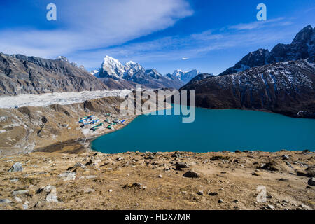 Vista aerea sul villaggio gokyo e gokyo lago da gokyo ri, il ghiacciaio Ngozumba e montagne coperte di neve in lontananza Foto Stock